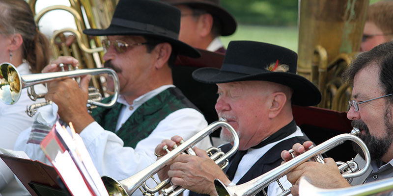 Men in hats and ethnic costumes playing trumpets in a brass band 