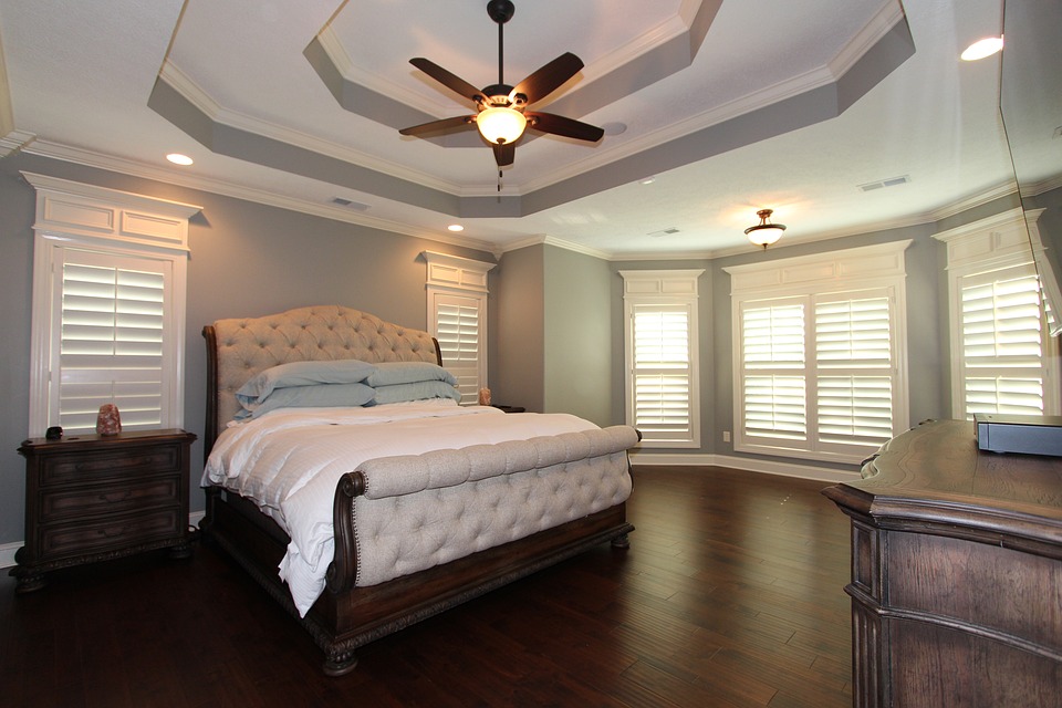 large white master bedroom with double tray ceiling and fan