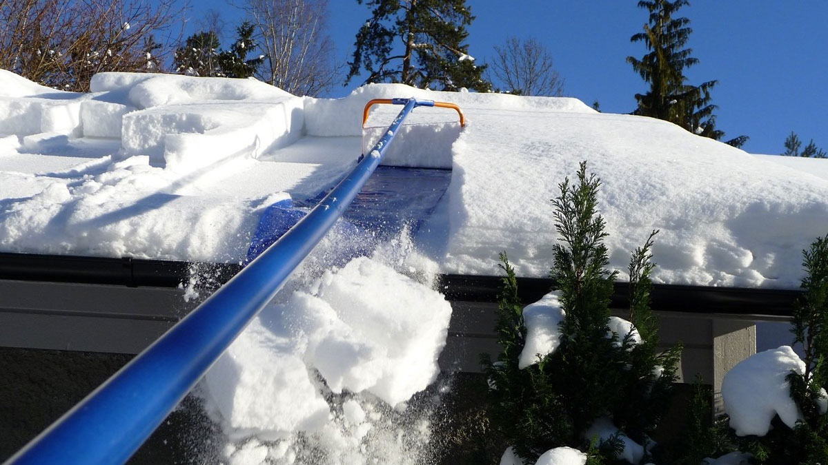 A roof rake raking snow off a house roof in winter
