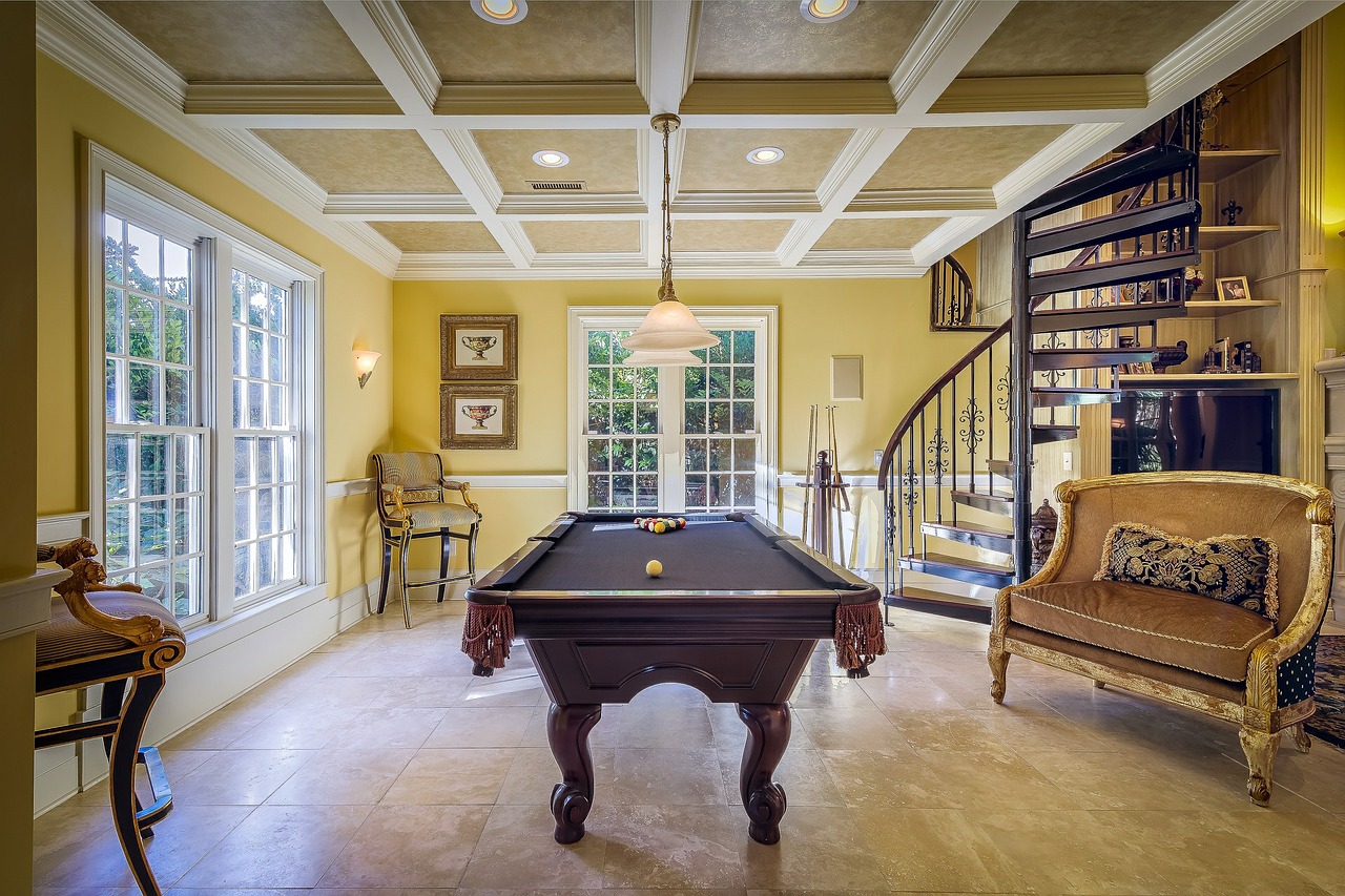 A pool table in a nicely decorated room with a coffered ceiling
